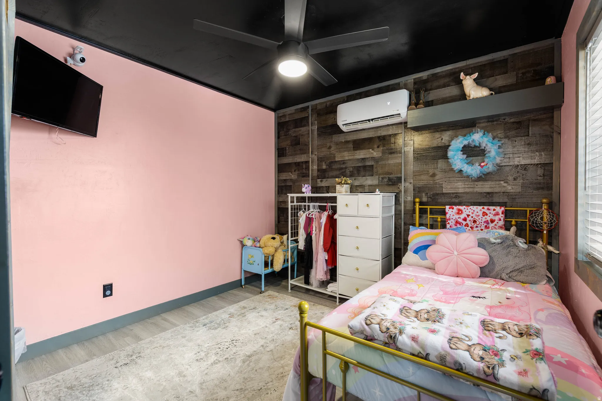 Interior room featuring a wood-finish accent wall, wall-mounted air conditioning unit, and a ceiling fan with integrated lighting