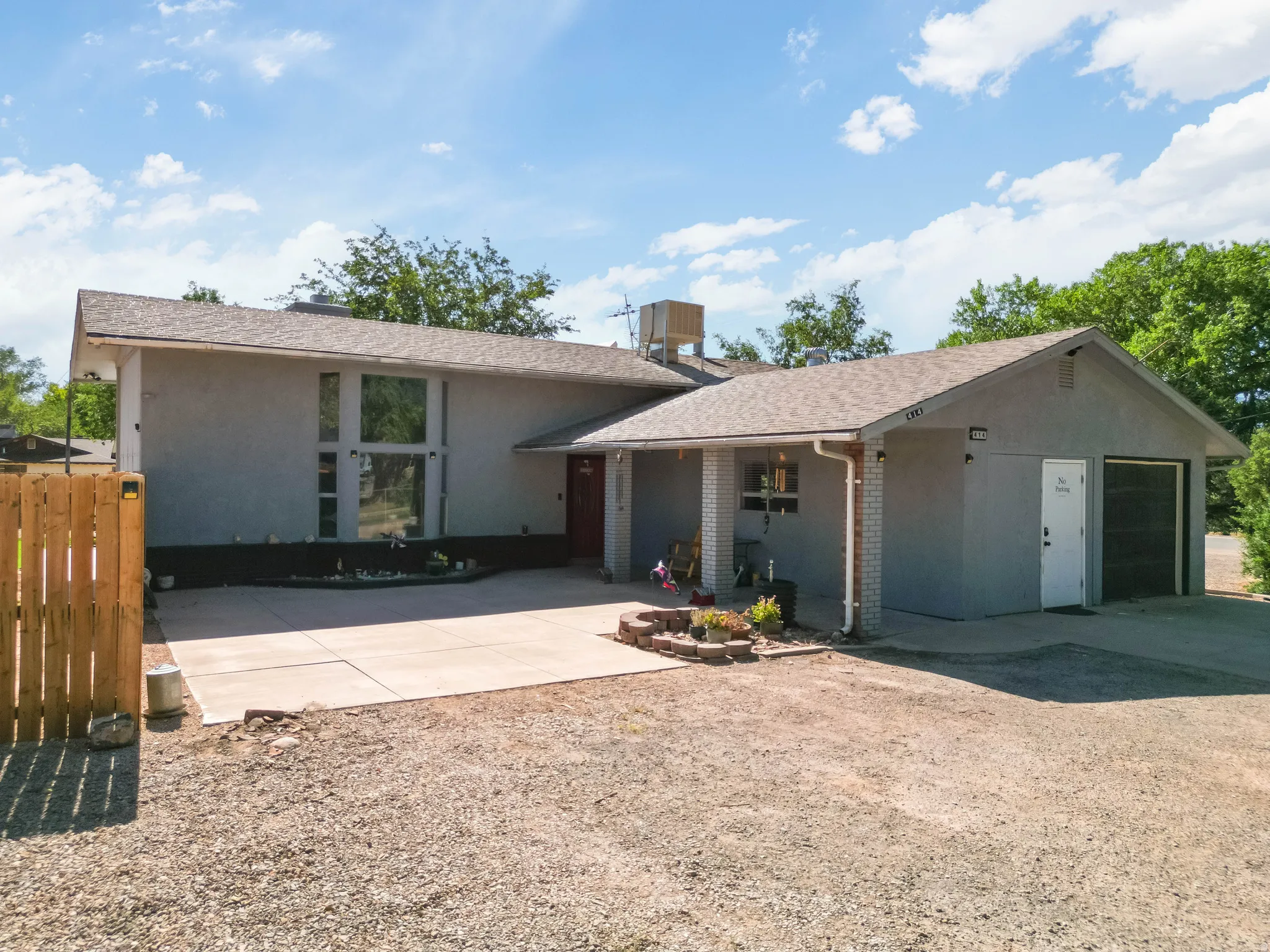 Contemporary exterior with a covered entry, large front window, attached garage, and paved driveway