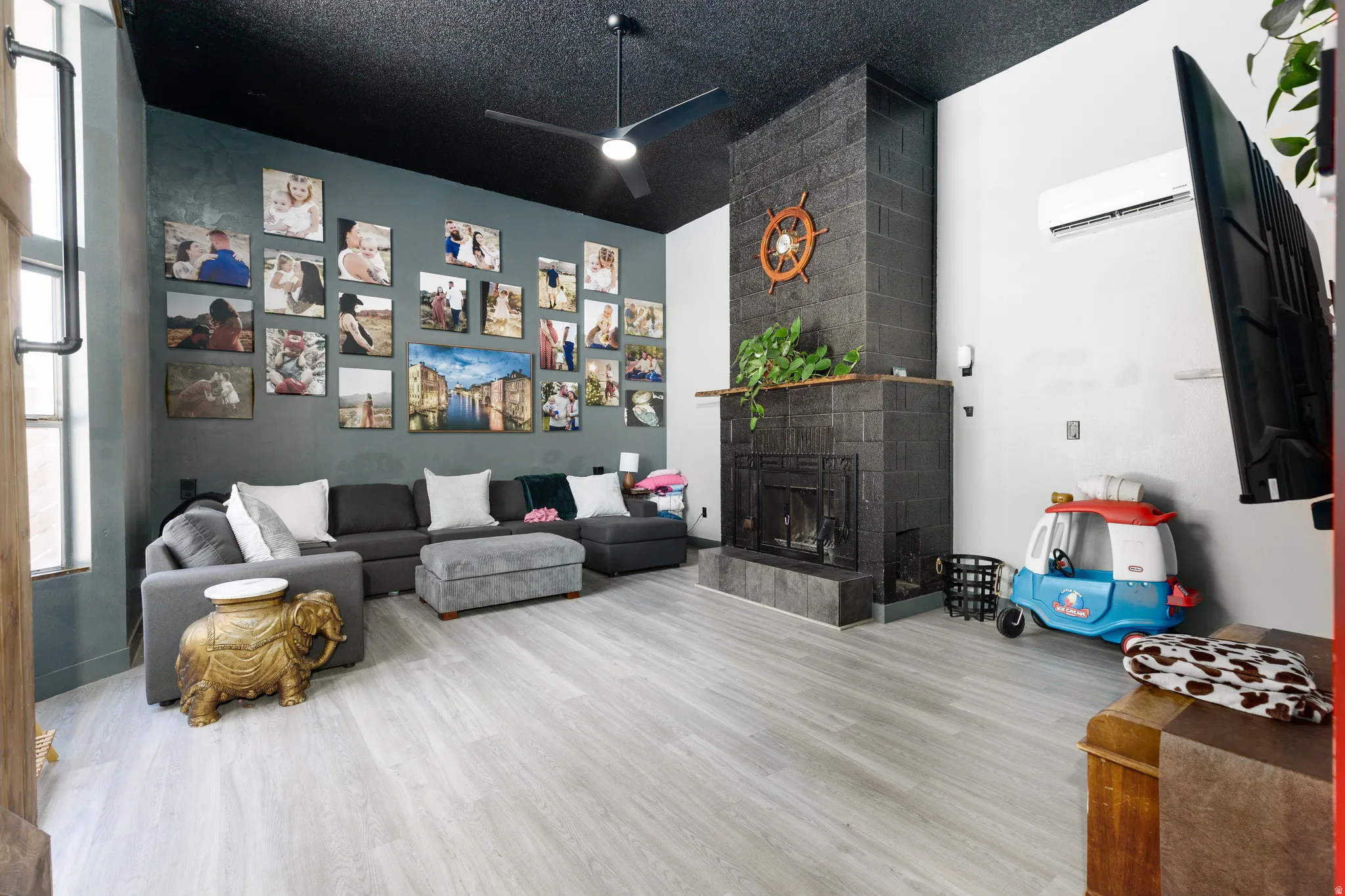 Spacious room featuring light wood-finish flooring, a dark accent wall, and a black ceiling