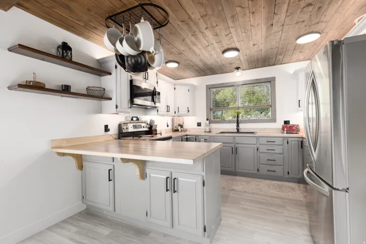 Kitchen featuring a wood-finish plank ceiling, light wood-finish countertops, grey lower cabinetry, white upper cabinetry, and stainless steel appliances