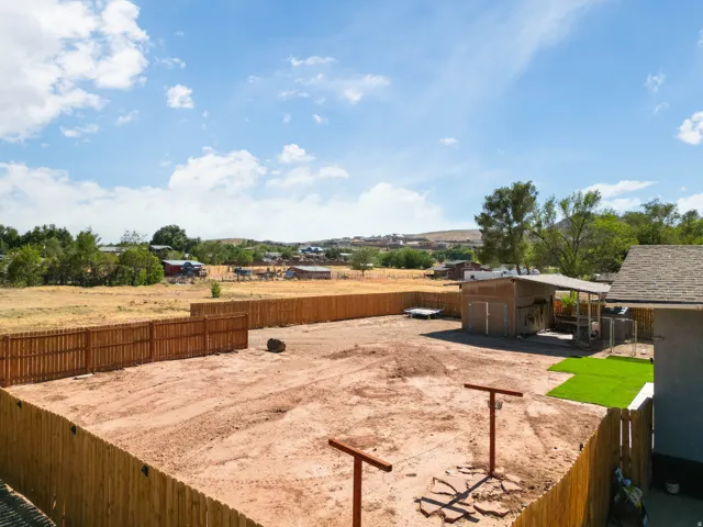 Large, fully fenced backyard with a newly installed wood privacy fence, featuring a covered outbuilding and a section of artificial turf