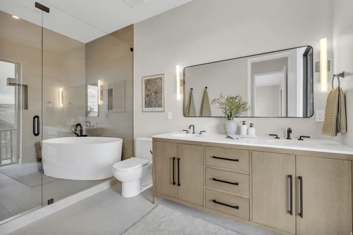 Contemporary bathroom featuring a freestanding tub, glass-enclosed shower, dual vanity with a light wood-finish, and a large rectangular mirror
