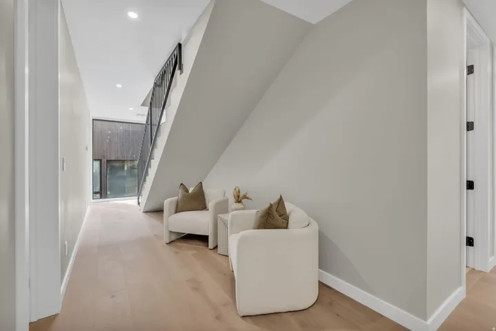 Modern staircase featuring black metal railings and light wood-finish flooring
