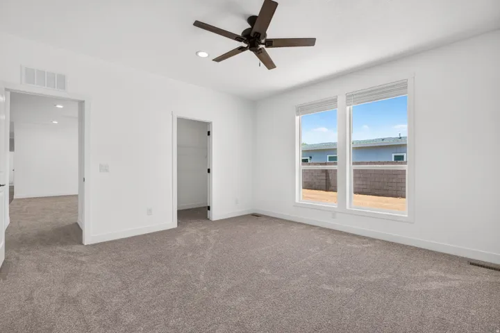 Spacious room featuring neutral carpeting, a dark-toned ceiling fan, recessed lighting, and two large windows with blinds