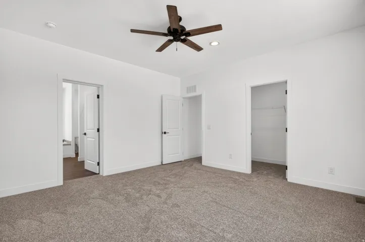 Spacious carpeted room featuring a ceiling fan with integrated lighting, recessed lighting, and multiple doorways
