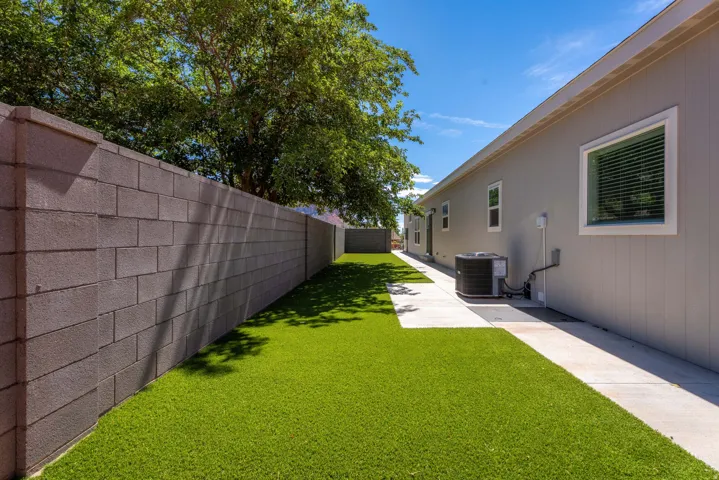 Exterior featuring a concrete block privacy wall, artificial turf, and a concrete pathway
