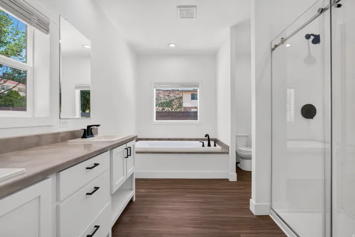 Bathroom featuring a dual vanity with a light-toned countertop, white cabinetry, and matte black hardware
