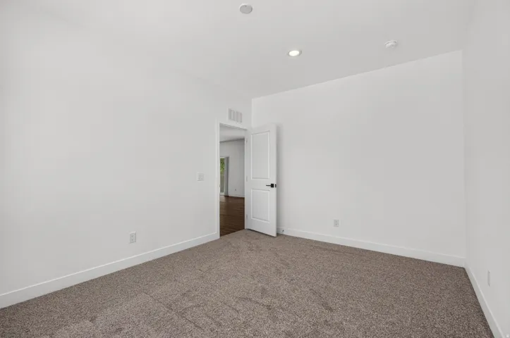 Carpeted room featuring white walls and recessed lighting