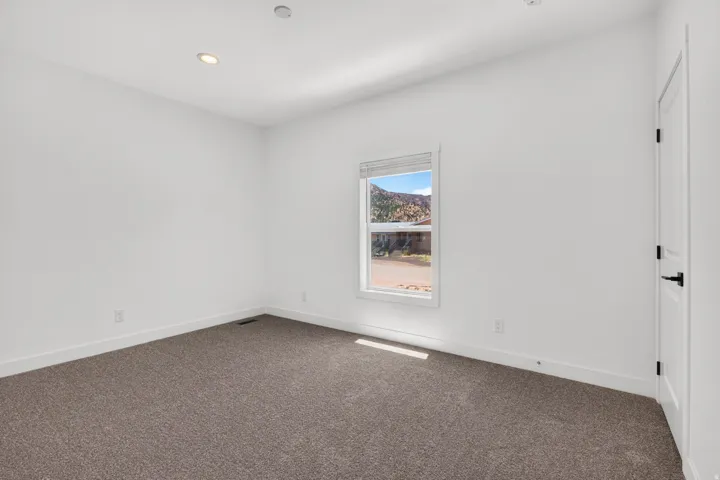 Carpeted room with white walls, recessed lighting, and a window framing a mountain backdrop