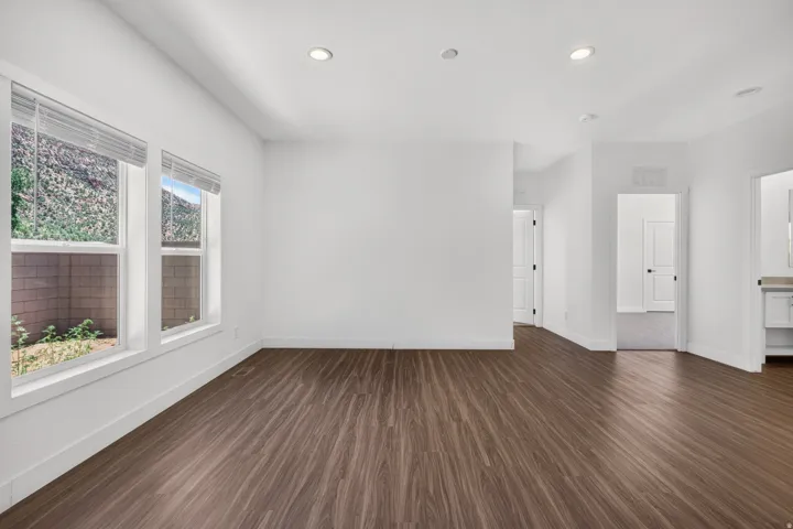Spacious room featuring wood-finish flooring, recessed lighting, and multiple windows with blinds