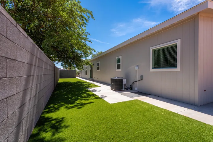 Low-maintenance artificial turf, concrete block perimeter wall, and a concrete paver walkway