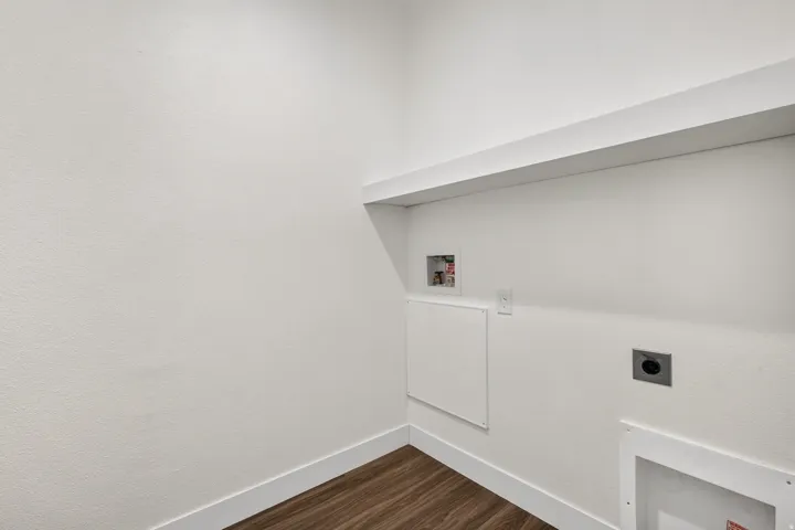 Dedicated utility space featuring a built-in white shelf, wood-finish flooring, and crisp white baseboards