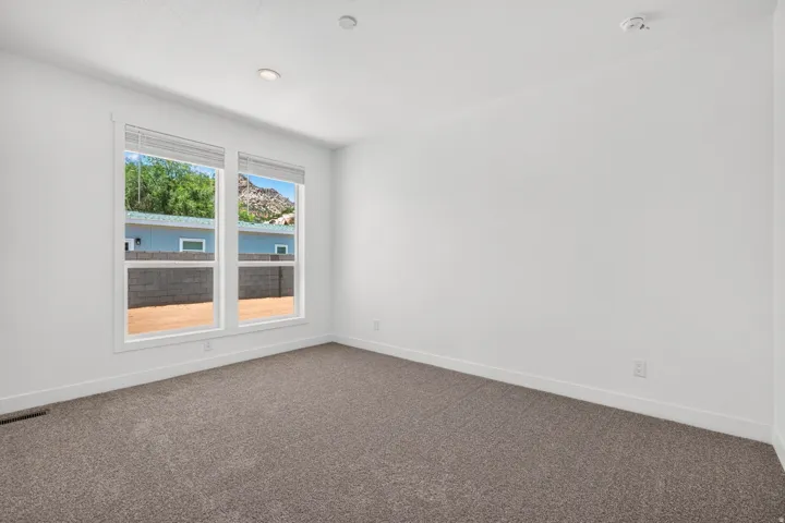 Spacious room featuring neutral carpet flooring, crisp white walls, and a large window with white trim
