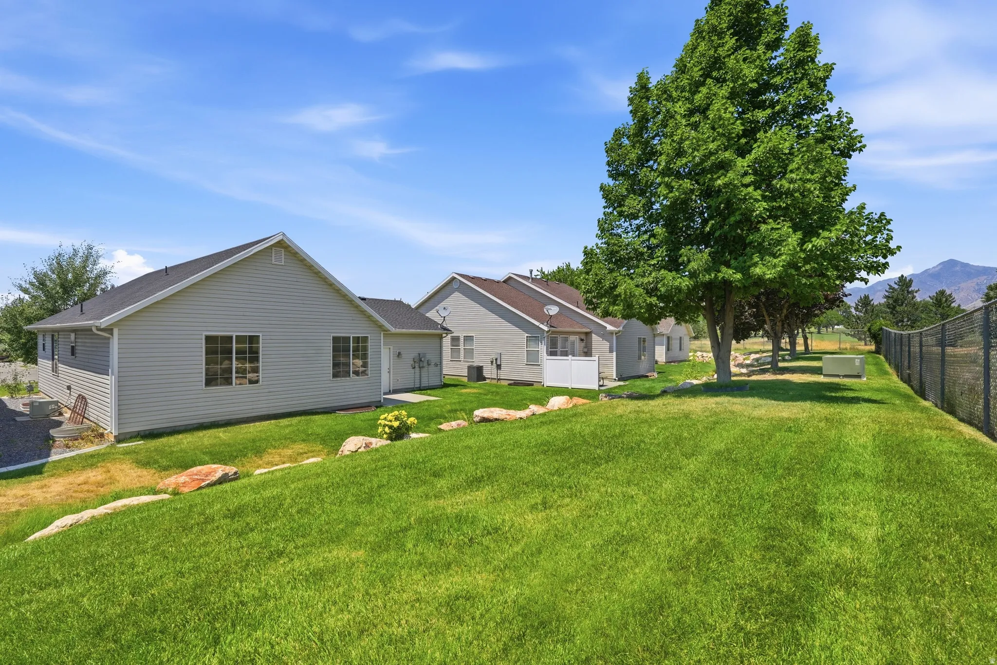 Expansive lawn bordered by mature trees and a chain-link fence