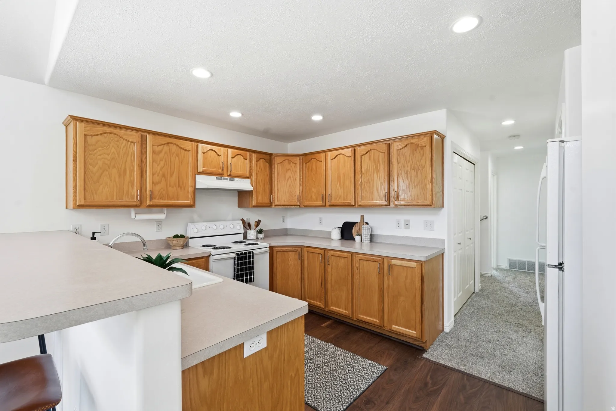 Kitchen featuring light wood cabinetry, light countertops, a built-in range, and a breakfast bar