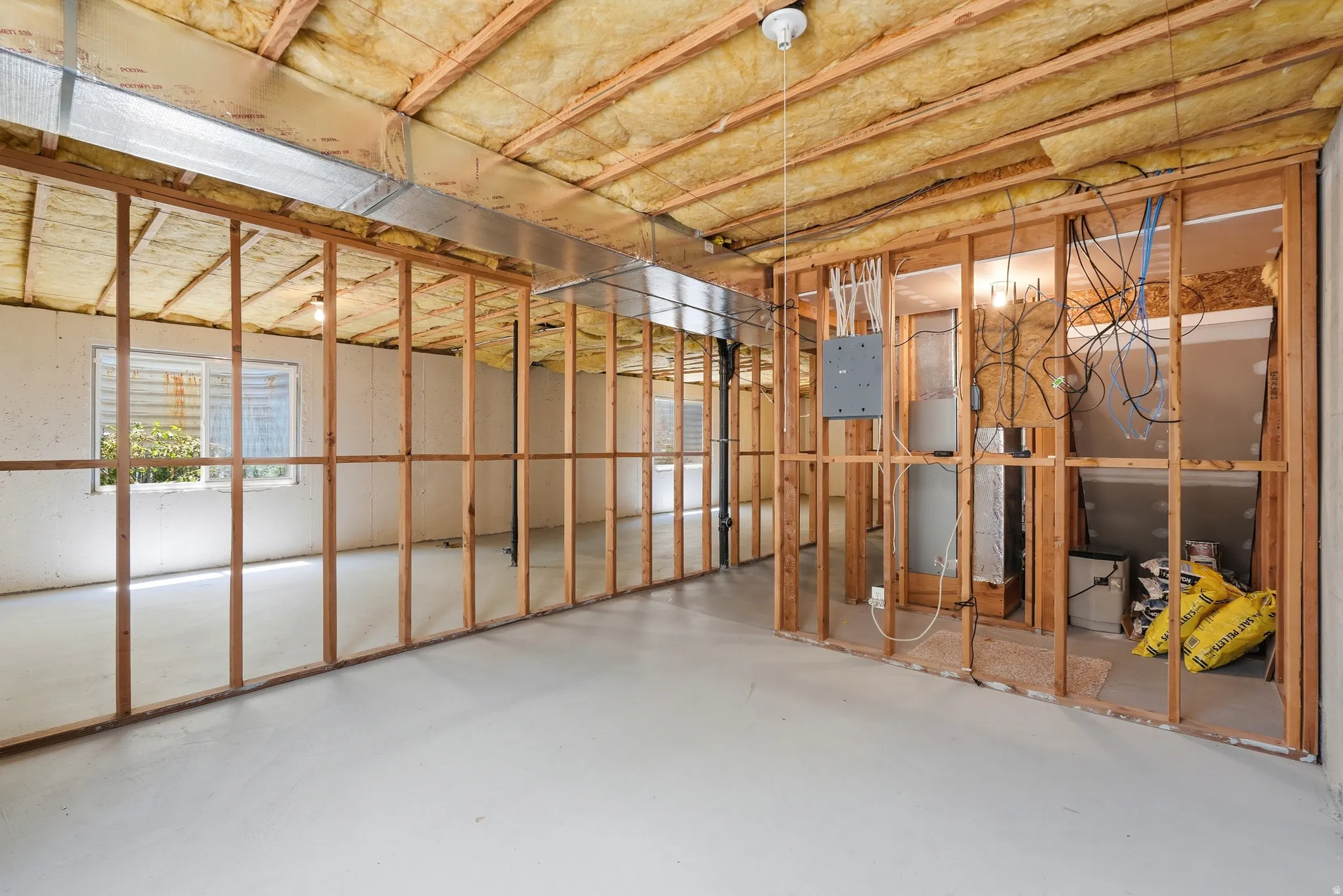 Unfinished basement offering exposed wood framing, insulated ceiling, painted concrete flooring, and multiple windows