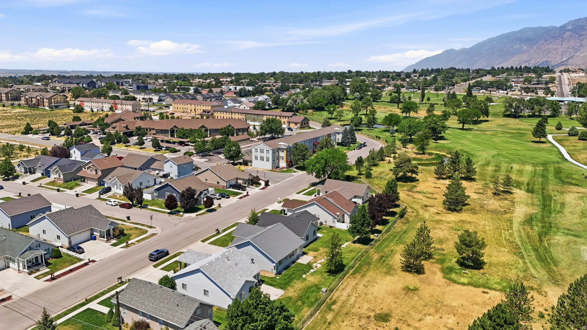 Aerial perspective showcasing a residential neighborhood with varied single-story homes and a multi-story building