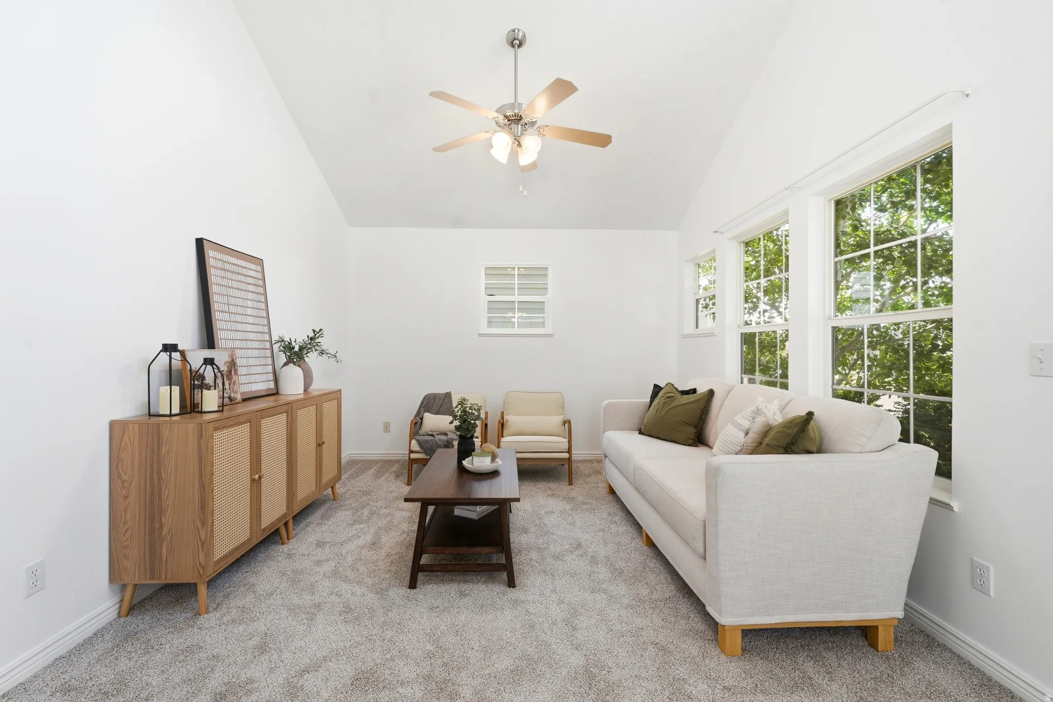 Vaulted ceiling with a ceiling fan, white paneled walls, and light gray carpet