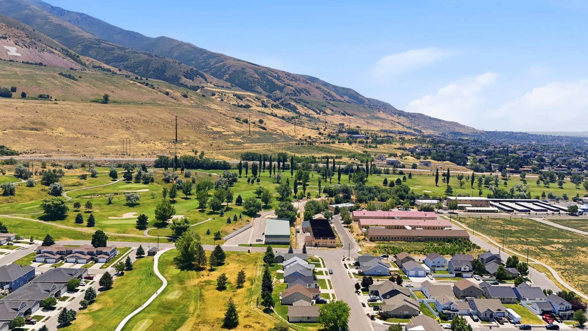 Aerial perspective featuring a residential area bordered by a golf course and a mountainous backdrop