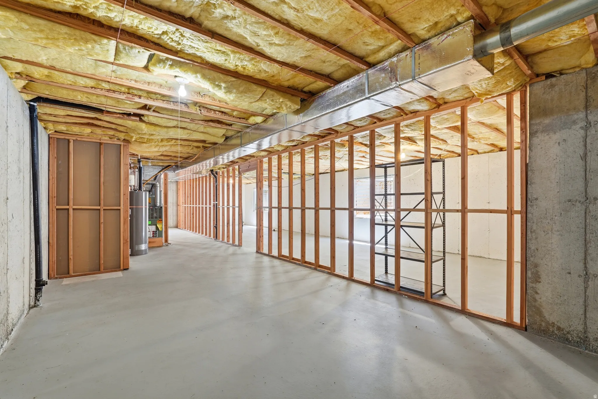 Unfinished basement featuring concrete flooring, exposed ceiling insulation, and wood framing for potential future rooms