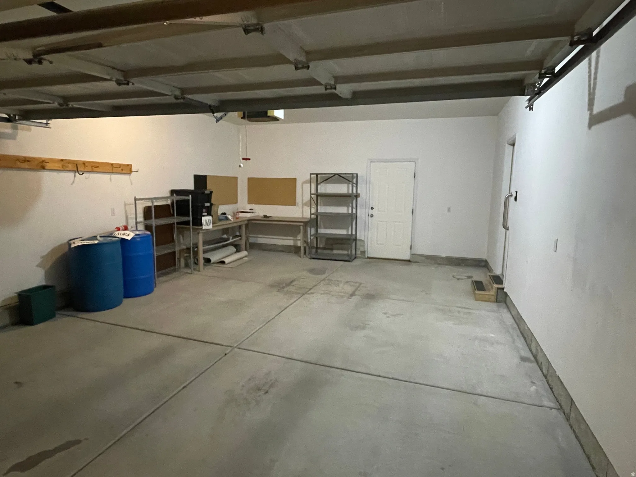 Spacious garage featuring a concrete floor, painted white walls, and an accessible side entry door