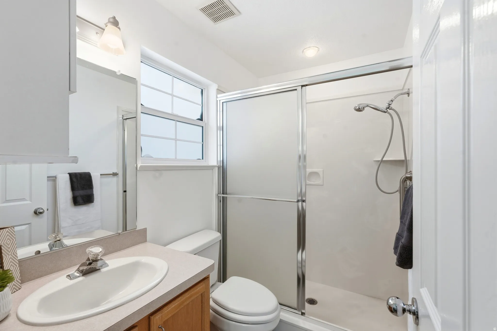 Bathroom featuring a single vanity with wood-finish cabinetry, a built-in sink, and a light-toned countertop