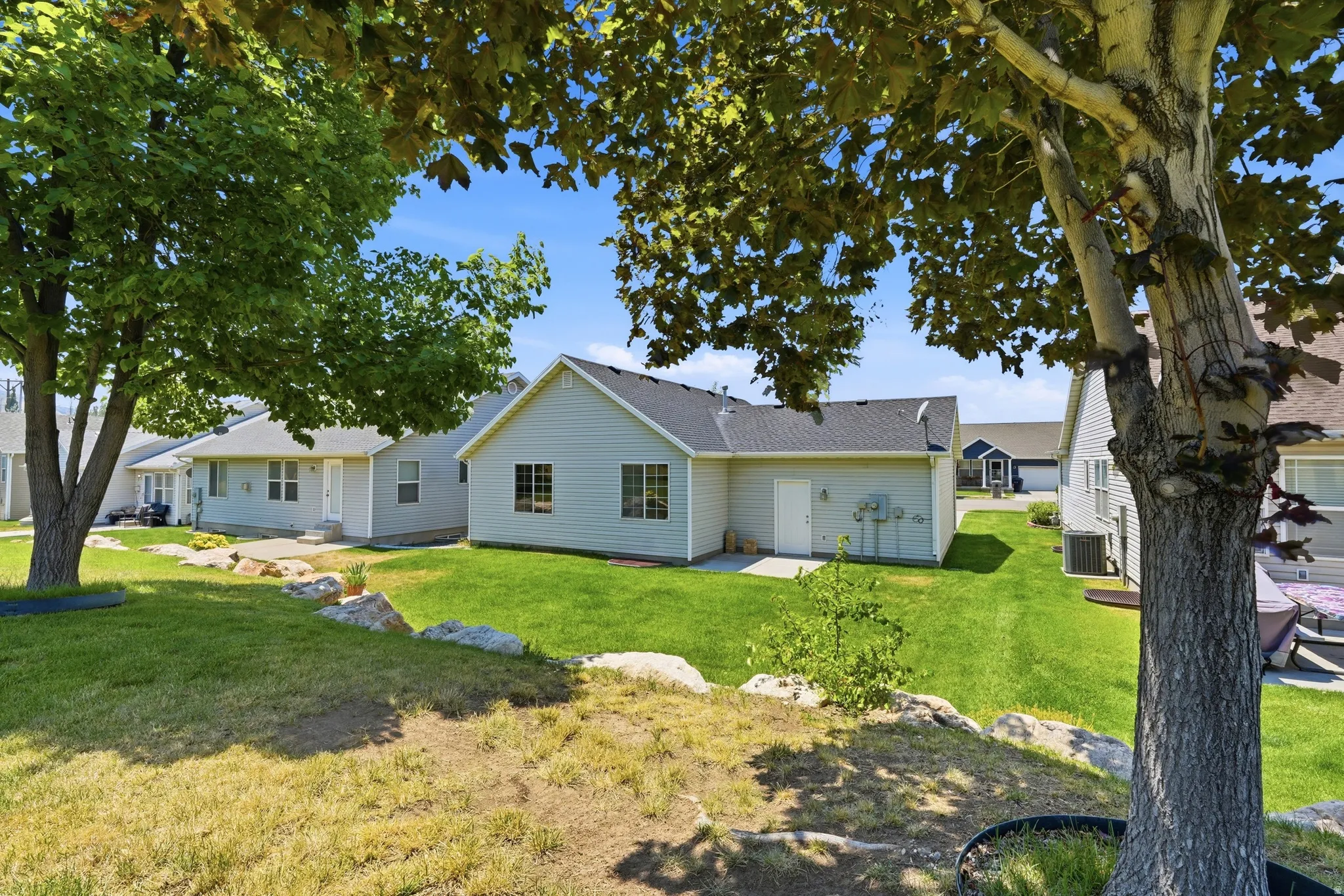 Manicured lawn with mature trees and stone landscaping accents