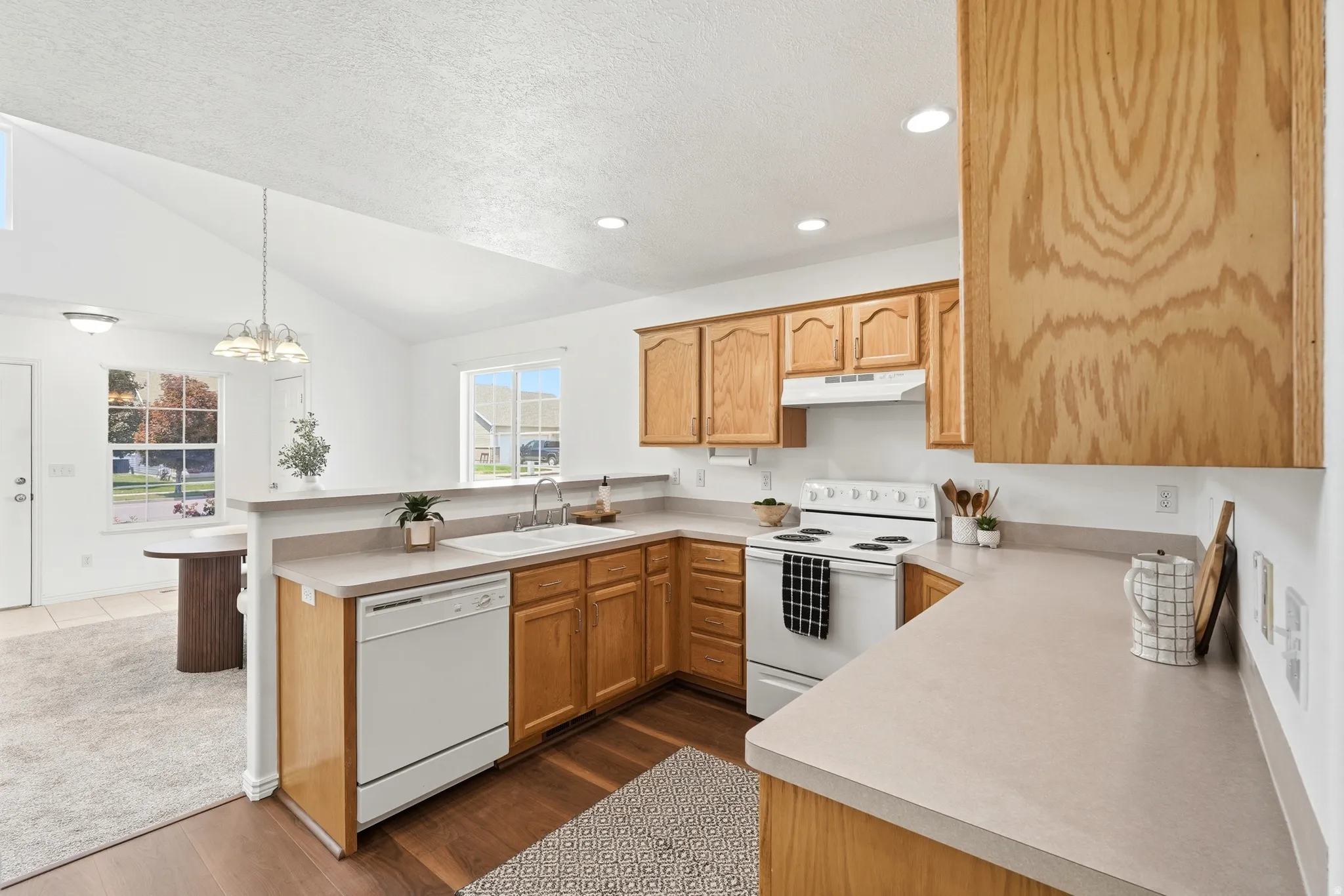 Kitchen featuring wood-finish cabinetry, solid surface countertops, and white appliances
