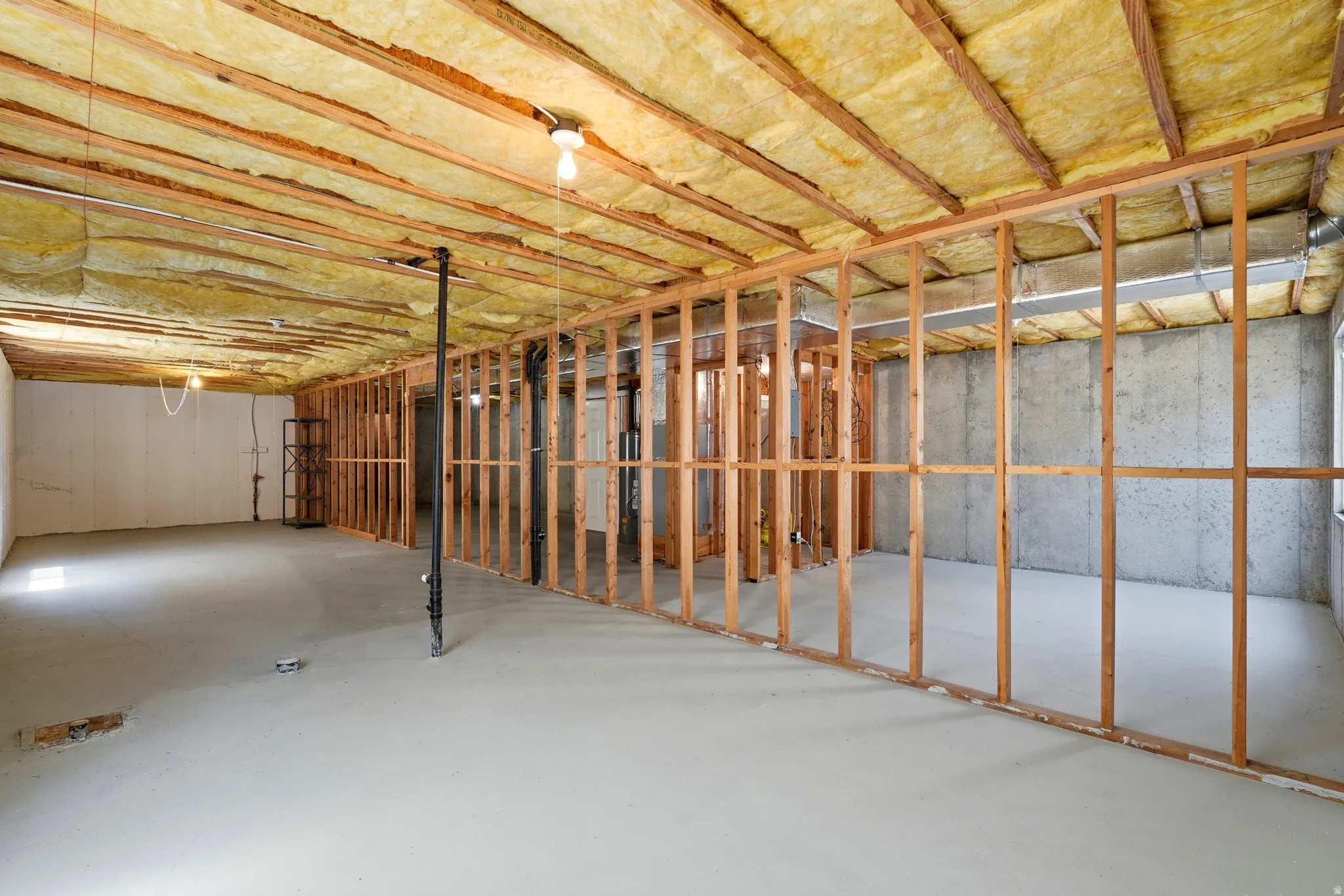 Unfinished basement featuring exposed wood framing, concrete walls, insulation, and a concrete floor