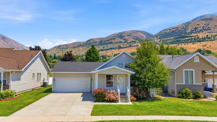Single-story home featuring light-colored siding, an attached garage, and a concrete driveway