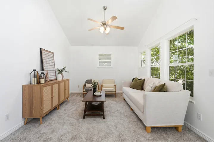 Vaulted ceiling with a ceiling fan, white paneled walls, and light gray carpet