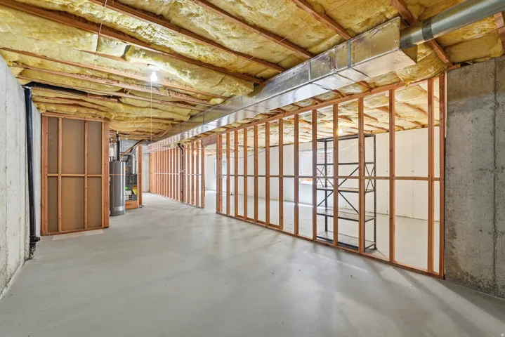 Unfinished basement featuring concrete flooring, exposed ceiling insulation, and wood framing for potential future rooms