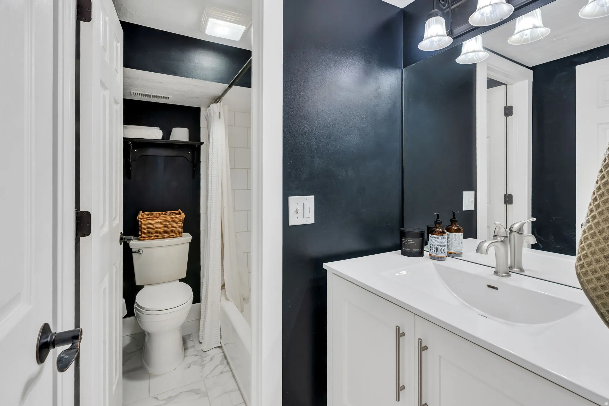 Full bathroom featuring a white vanity with an integrated sink, brushed nickel faucet, and a large wall mirror