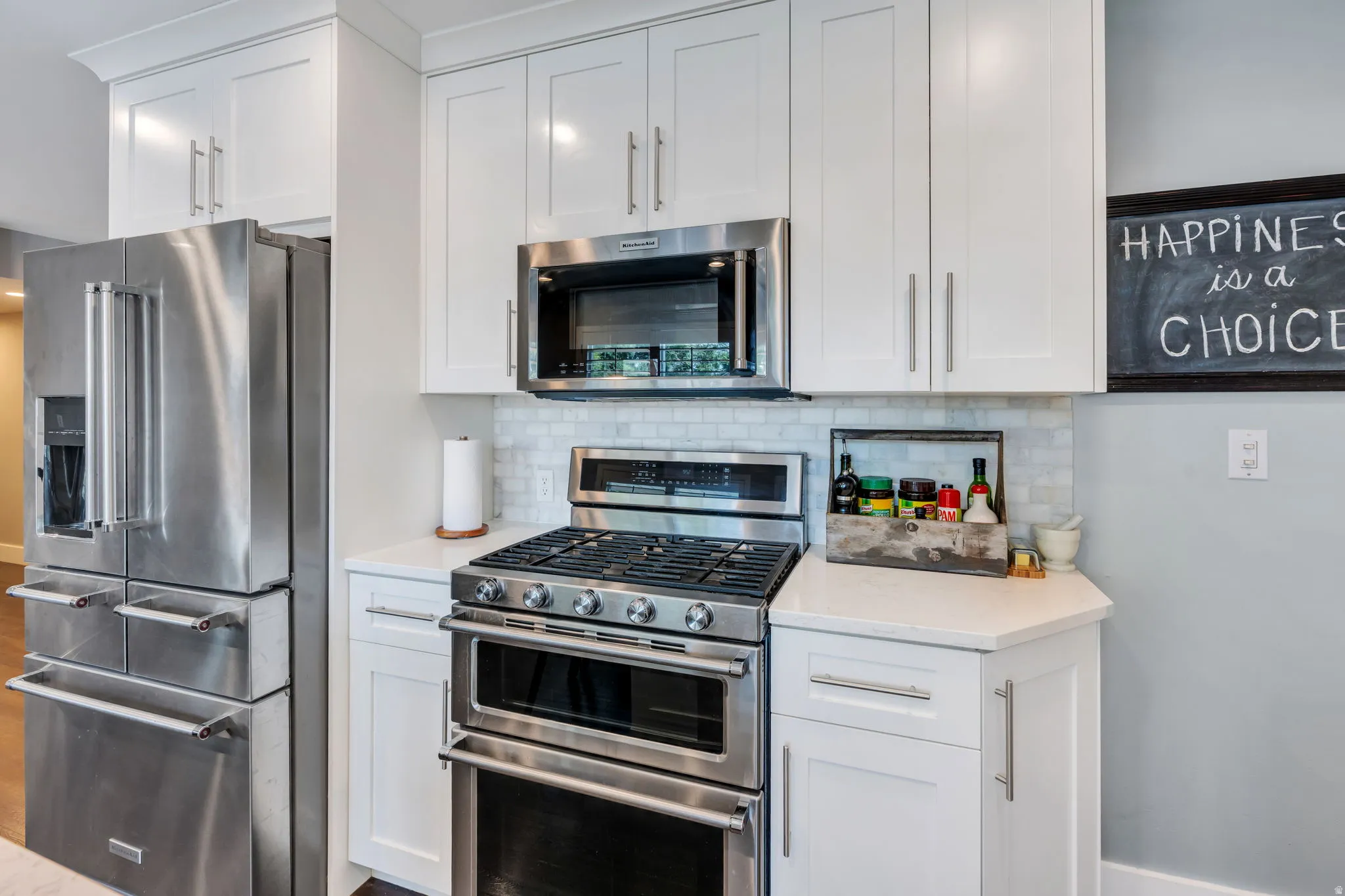 Kitchen featuring stainless steel appliances, white shaker-style cabinetry, a gas range with a double oven, and a marble backsplash