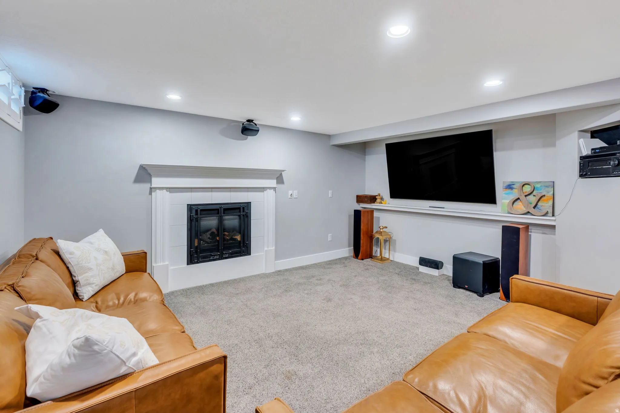 Spacious entertainment area featuring a built-in gas fireplace with a white mantel, recessed lighting, and light grey carpeting