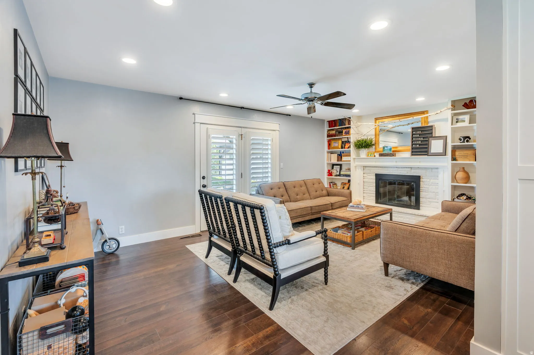 Spacious living area featuring built in cabinetry, wood burning fireplace, dark wood-finish flooring, and recessed lighting.