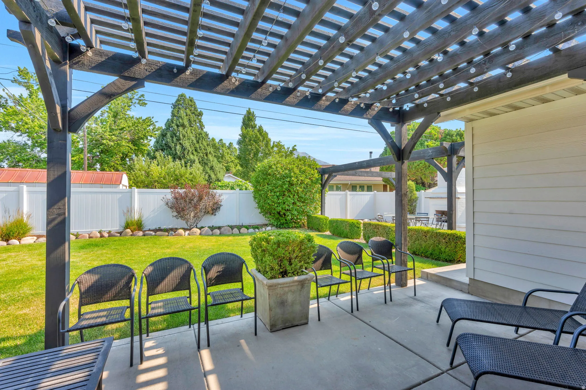 Expansive outdoor patio with a dark wood pergola and string lights