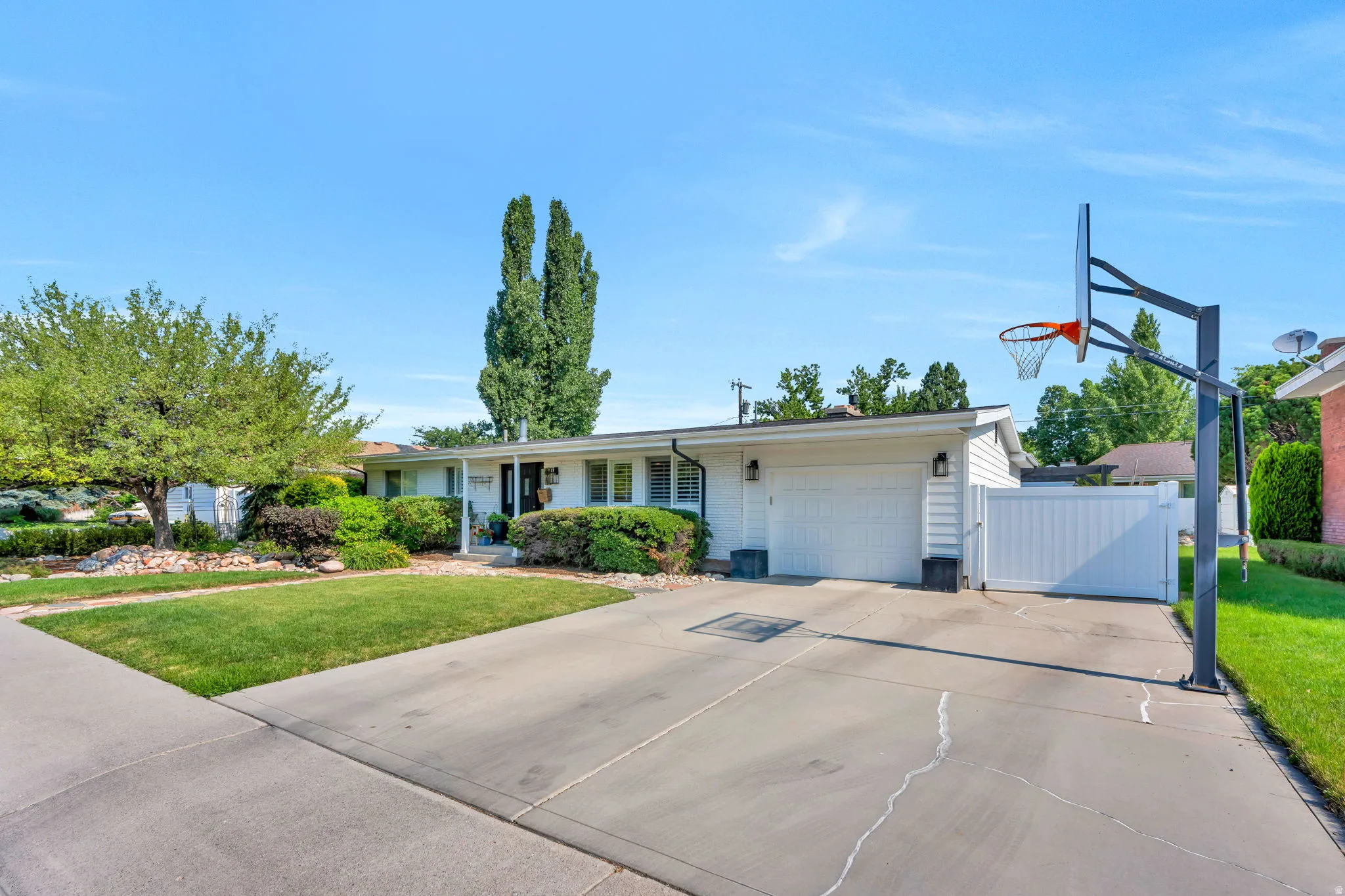 Ranch-style residence featuring a white exterior, attached two-car deep garage, and a concrete driveway