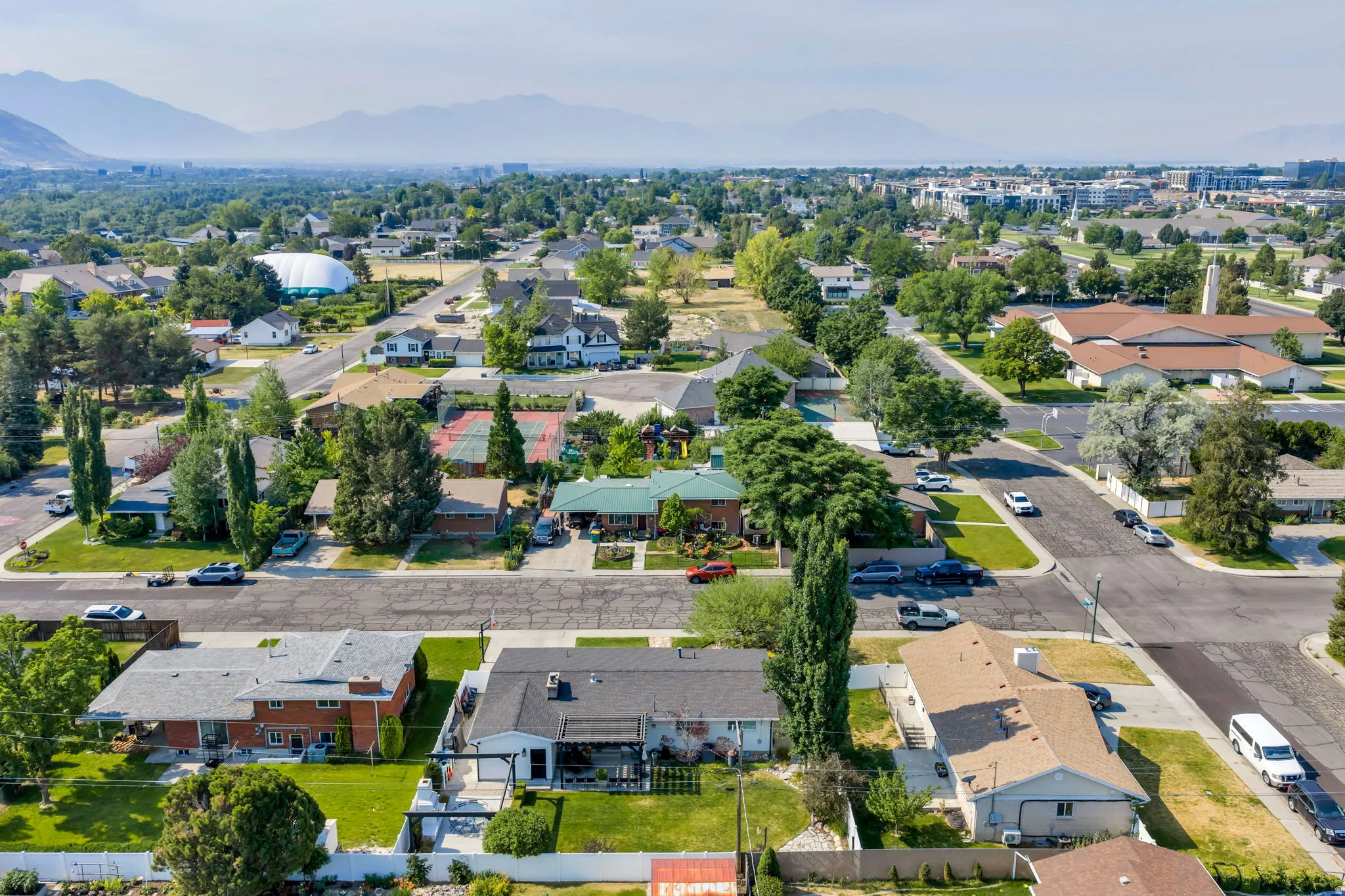 Aerial perspective showcasing a residential neighborhood with tree-lined streets and mountain backdrops.  Close to University Mall.
