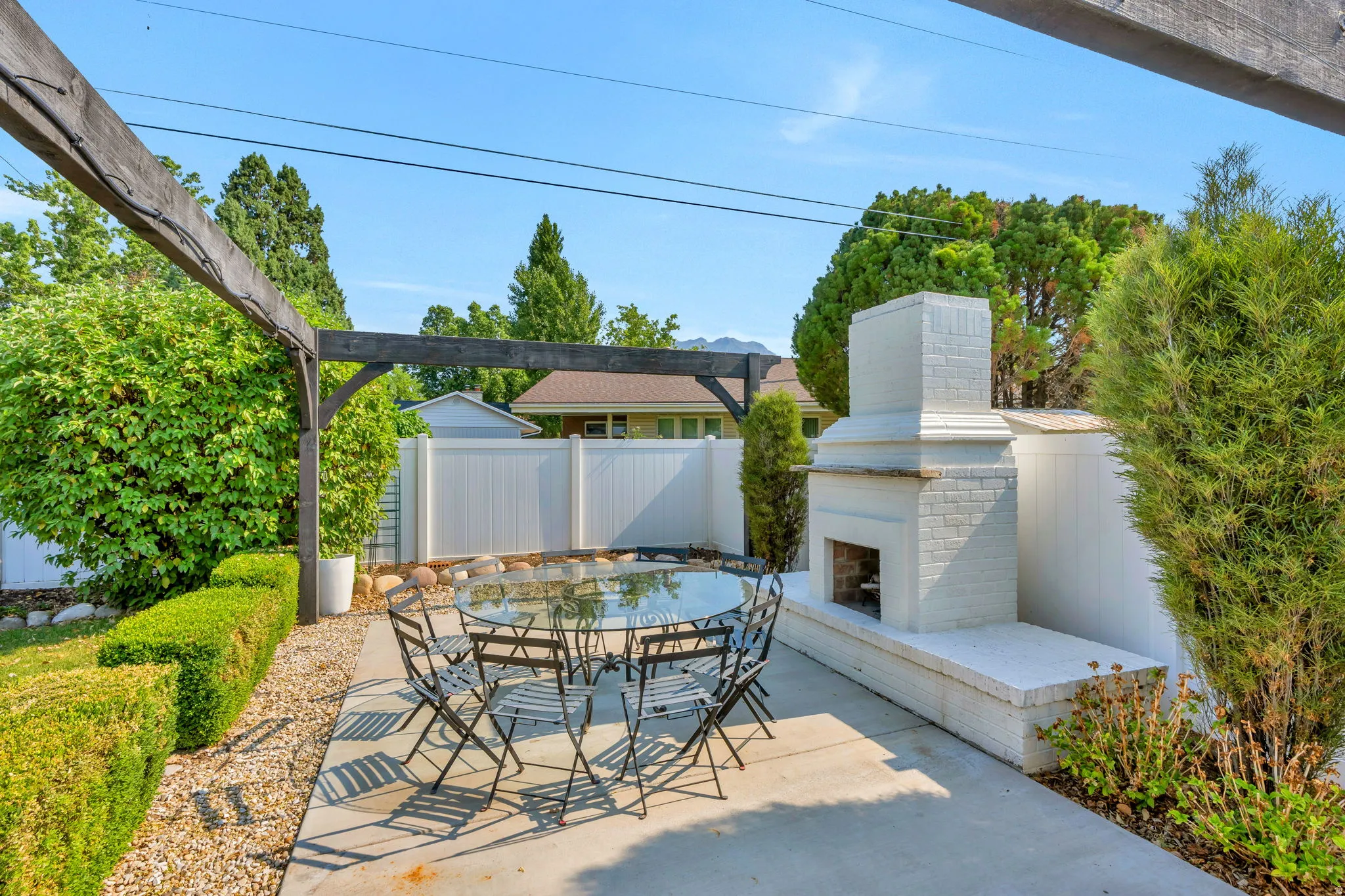 Outdoor patio featuring a built-in white brick fireplace, concrete paving, and a dark wood pergola