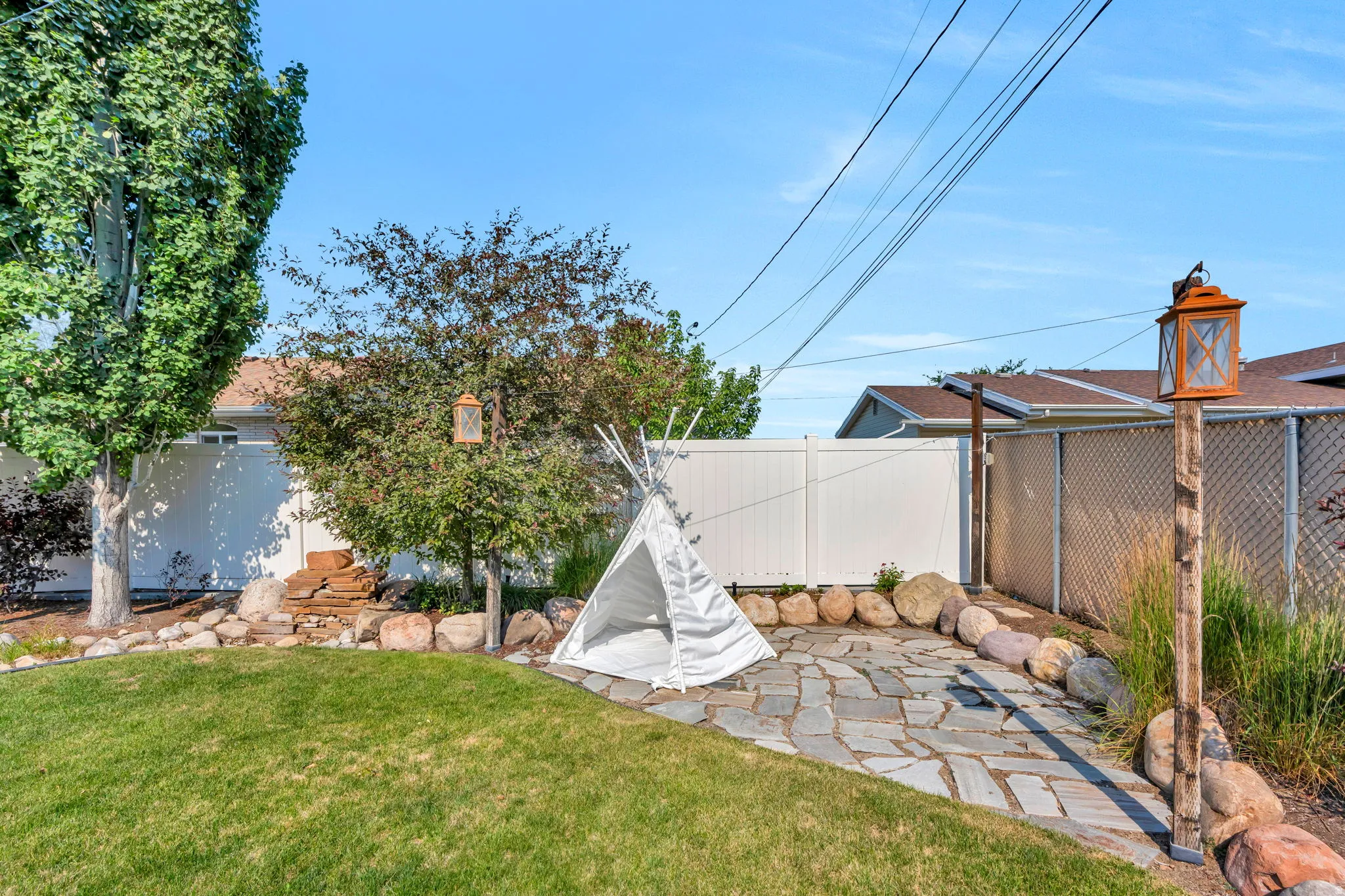 Backyard featuring a flagstone patio, manicured lawn, and mature trees