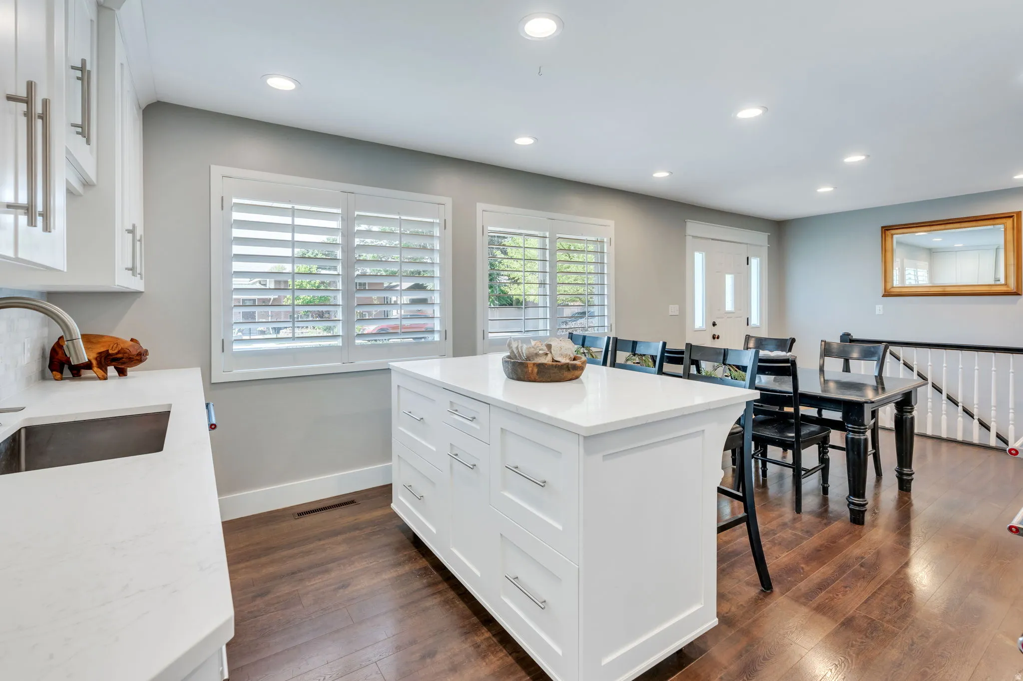 Kitchen featuring a white movable island with drawers, white shaker-style cabinetry, and quartzite countertops