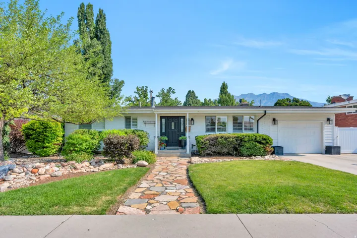 Ranch-style exterior with a flagstone walkway, mature landscaping, and a two-car deep garage