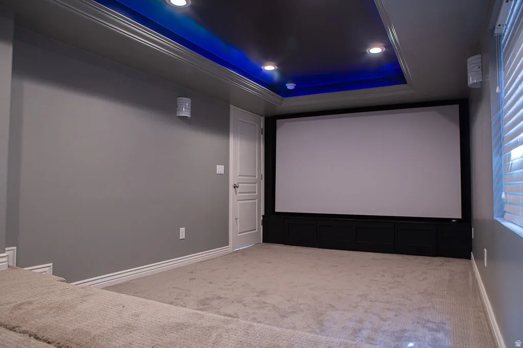 Dedicated entertainment space featuring a large projection screen, recessed ceiling lighting, and layered tray ceiling with accent lighting