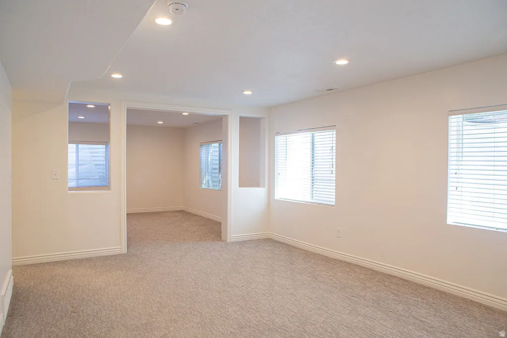 Spacious room featuring neutral carpet, recessed lighting, white trim, and multiple windows with blinds