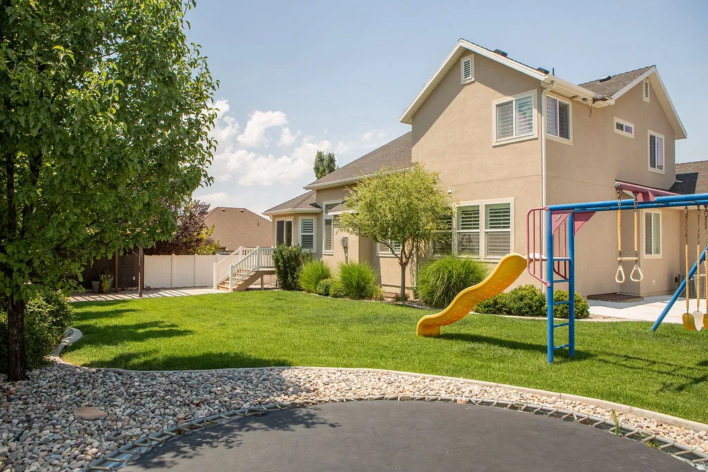Spacious backyard featuring a manicured lawn, established perimeter landscaping, and a white privacy fence