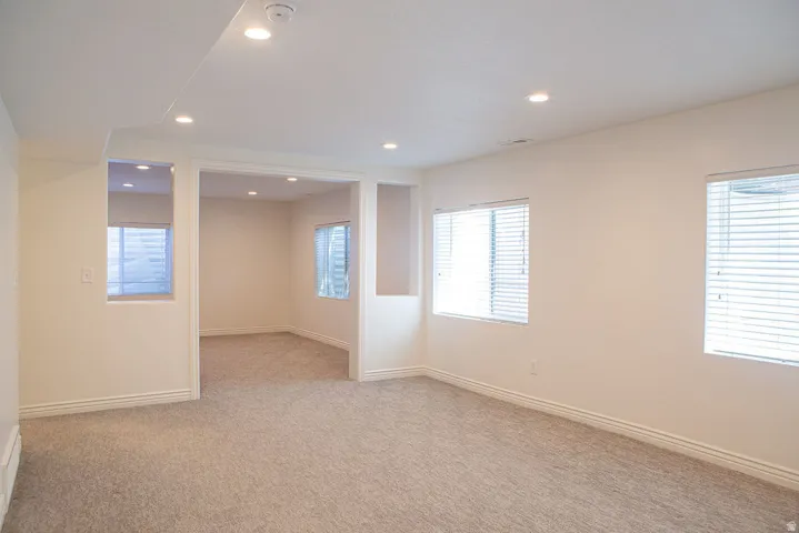 Spacious room featuring neutral carpet, recessed lighting, white trim, and multiple windows with blinds