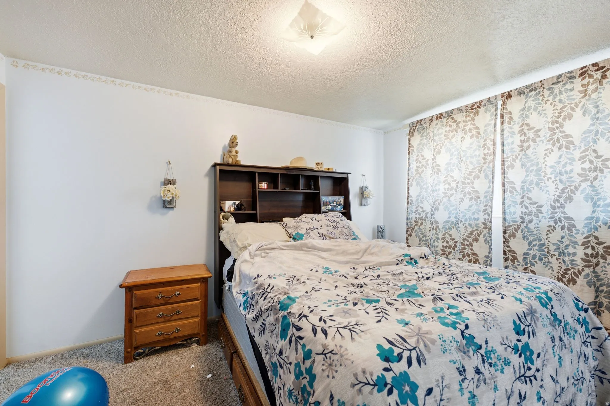 Carpeted room with a textured ceiling and a flush-mount ceiling light fixture