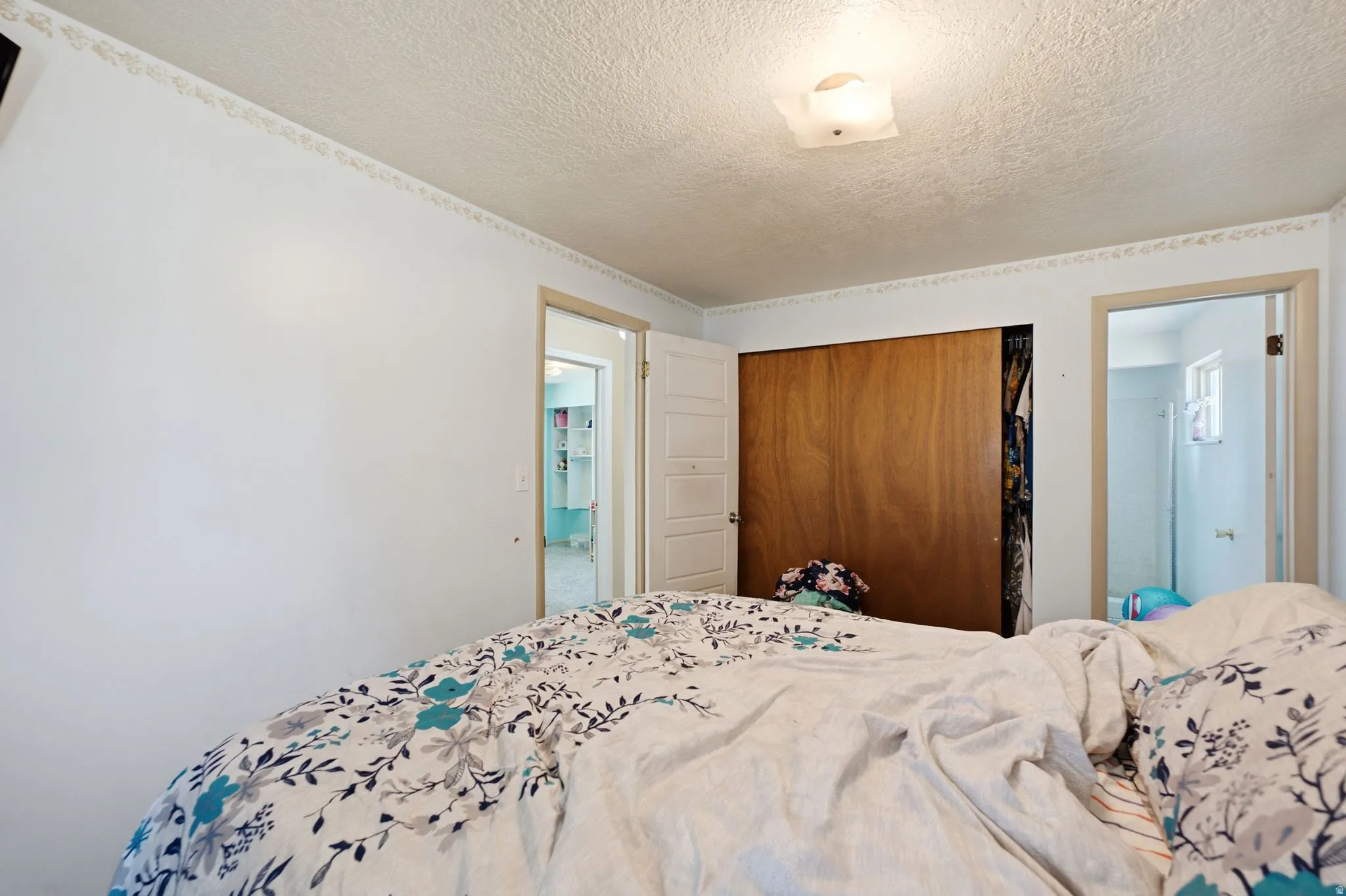 Bedroom featuring a wood-panel closet with sliding doors, white walls, and a textured ceiling