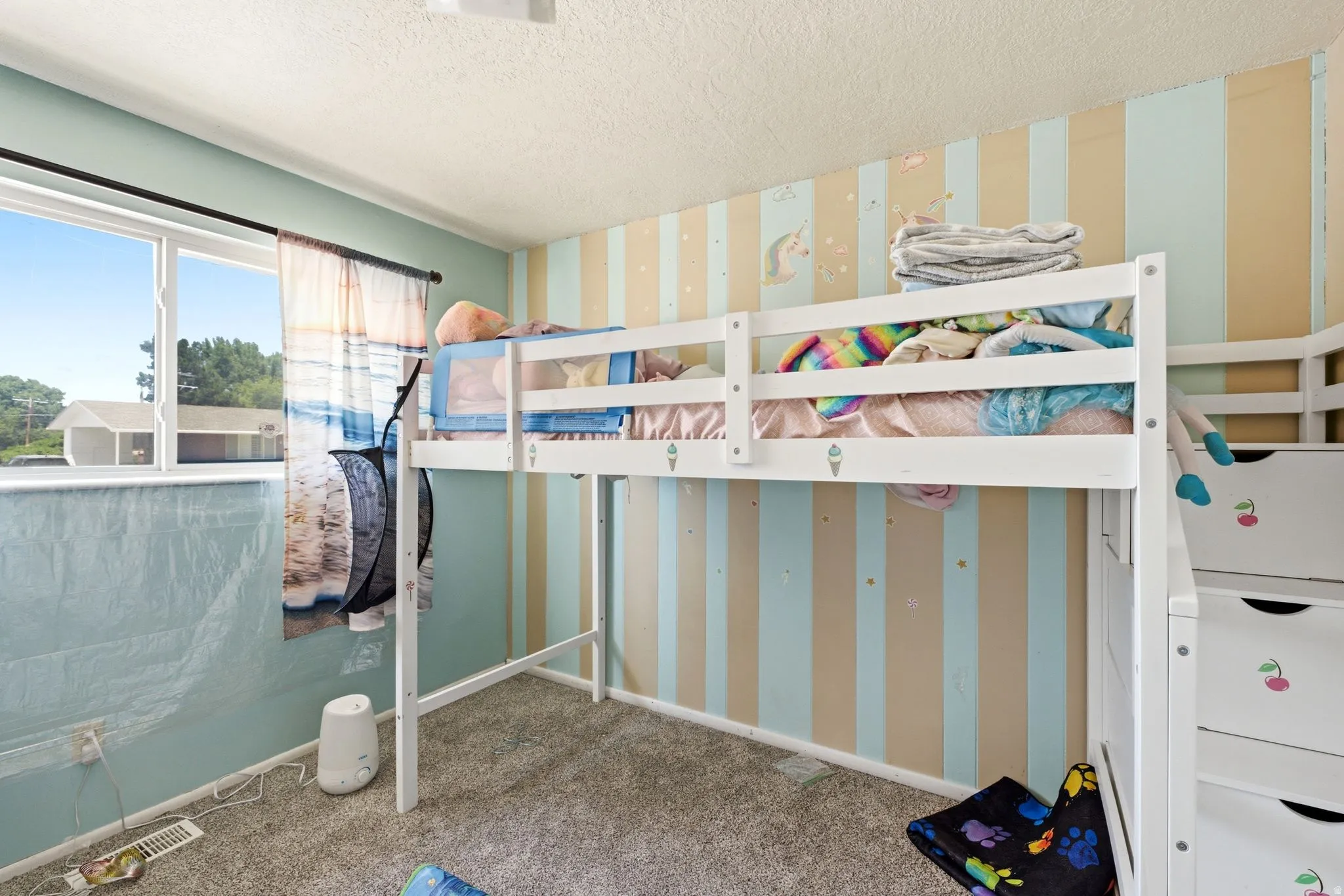 Room featuring a large window, textured gray carpeting, and a unique striped wall treatment